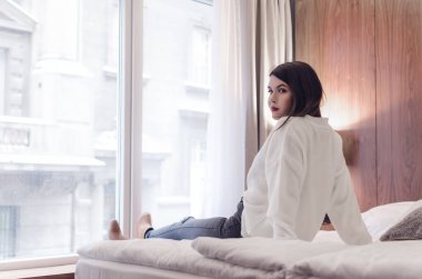 Yan görünümü shot bir genç güzel kadın yatakta oturuyordu. Rahatlama ve dinlenme kavramı