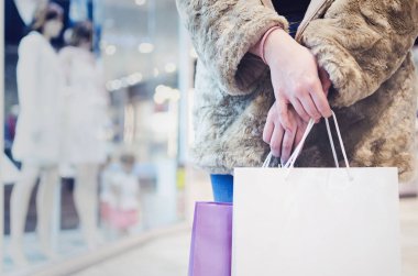 Alışveriş torbaları ve alışveriş arka plan penceresinde olan neşeli kadın