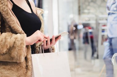Eller, beyaz torbalarda bir akıllı telefon ile alışveriş alışveriş kadın
