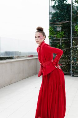 Çatıda poz tasarımcı uzun Kırmızı elbiseli genç modeli