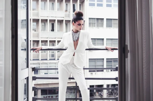 young woman in designer white suit posing on balcony