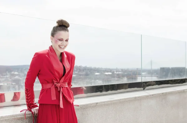 ポーズの屋根の上の赤いドレスの若い笑顔ブルネットの女性 — ストック写真
