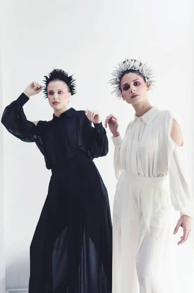 Two fashionable women in designer clothes posing in studio