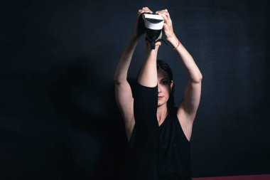 Fitness 'e adanmıştır. Siyah spor giyim giymiş güzel bir bayanın tek bacağı siyah arka planda esneme hareketleri. Kopya alanı olan ilan panosu resmi