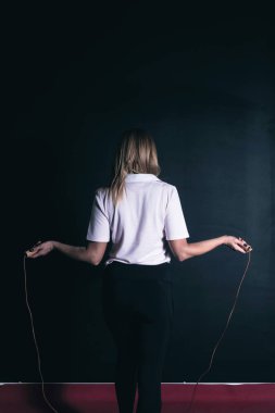 Beden dersinde ip atlayan sarışın bir kadının arka görüntüsü.