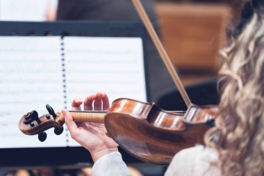 Güzel genç bir kadın keman çalıyor. Arkaplanda sayfa müziği