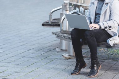 Parktaki bankta otururken dizüstü bilgisayarda çalışan yakışıklı genç müdürün kırpılmış görüntüsü, iş hayatı dengesi kavramı. Kopyalama alanı ile resim