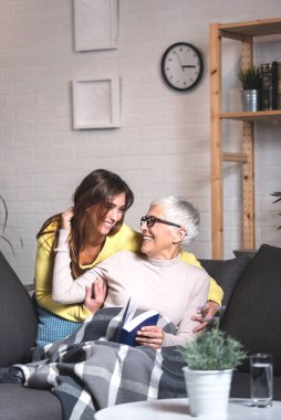 Büyükanne ve torun kanepede konuşup gülüyorlar.