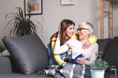 Büyükanne ve torun kanepede konuşup gülüyorlar.