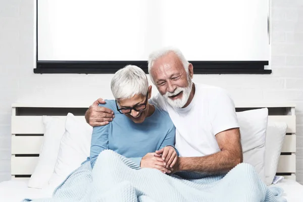 一对浪漫的老夫妇躺在床上笑着 — 图库照片