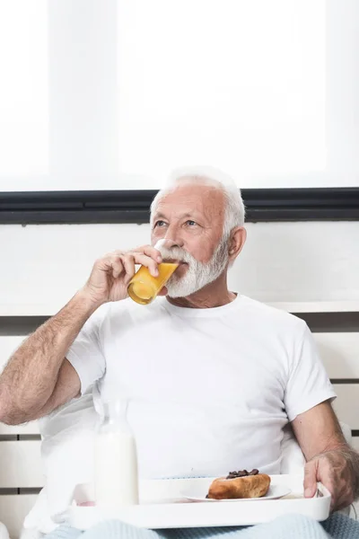 Lykkelig Senior Mand Der Spiser Morgenmad Sengen Efter Vågne Drikker - Stock-foto