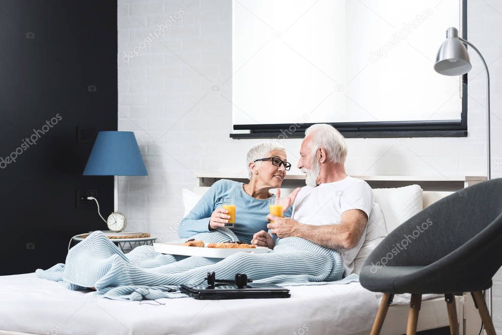 Joyful senior couple having healthy breakfast in their bedroom