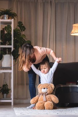 Genç bekar anne bebeğinin kollarını tutuyor ve ona yürümeyi öğretiyor. Hayatın anlamı kavramı