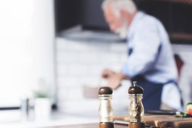 Arka planda, önlükle yemek pişiren yaşlı bekar adam bulanıklaştı.
