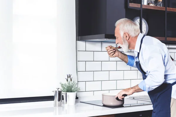 Più Vecchio Barbuto Bell Uomo Assaggia Cibo Cucina Una Cucina — Foto Stock