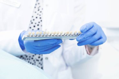 Doktorların ellerini eldivenle kapayın. Ellerinde beyaza izole edilmiş diş tonlarının paleti olsun. Boşluk resmini kopyala