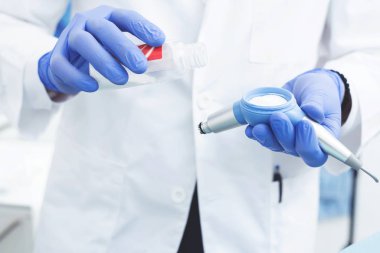 Kesilmiş görüntü doktorlarının elleri, diş fırçalamak için kumu ve şişeyi tutuyor. Boşluğu kopyala