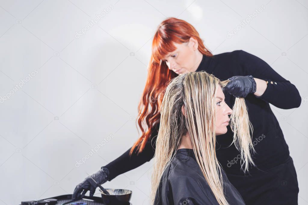 Professional hairdresser dyeing hair of her client. Space for text