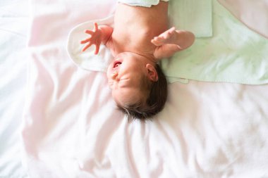 Bebek kendini bebek bezine sararken ağlıyor. Resmin üzerine kopyalama alanı ekle