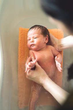 Küçük bebek önce annelerin ellerinde yıkanıyor.