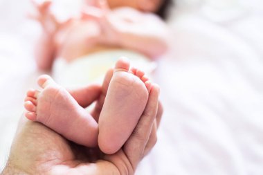 Babasının yeni doğmuş kızının ayaklarını tutarken çekilmiş bir fotoğrafı var. Uzay resmini kopyala. Bulanık bebek, yakın plan bebek tabanı