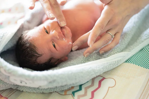 妈妈用手把婴儿油涂在新生儿脸上的剪影 — 图库照片