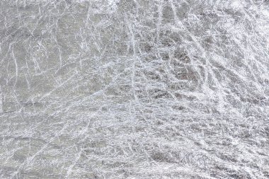 Buruşmuş gümüş folyo dokusu. Kaba metal dekoratif malzeme tabakası. Parlak soyut arkaplan.