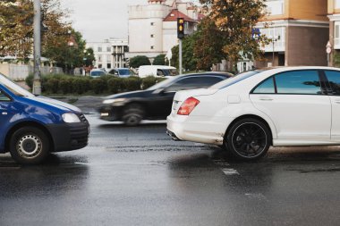 Şehrin yaya geçidinde iki araba var. Trafik ihlali konsepti fotoğrafı. Yağmurlu bir günde beyaz araba. Mesafeyi koru. Kazadan önce. Yolda davetsiz misafir var..