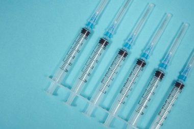 Turkuaz arka planda arka arkaya altı boş şırınga. Tıbbi geçmişi var. Bir hasta için tedavi yöntemi. Uyuşturucu bağımlısı konsepti fotoğrafı. Coronavirüs tedavisi.