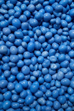 Mavi jöleli çikolatalar. Renkli hava akımları. Mavi jöleli fasulye sürüme arka planı. Şekerci. Dikey resim.