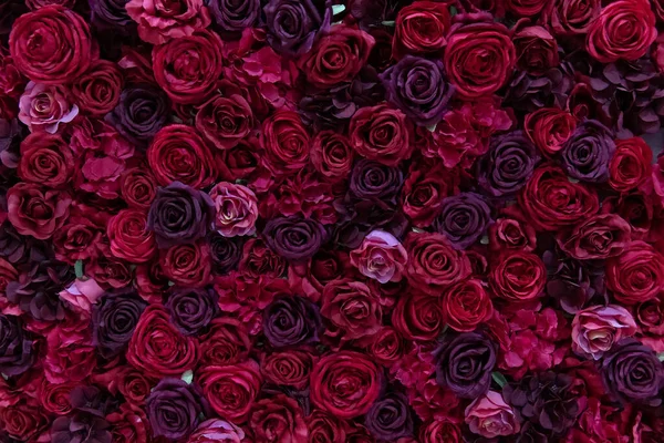 Red and purple paper roses background. Wall made of paper flowers. Floral interior.