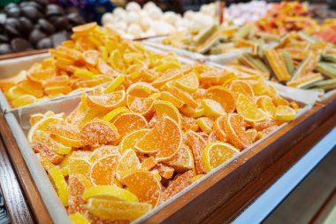 Tezgahın üzerinde şekerle kaplı turuncu ve sarı marmelatlı şekerler. Şekerci dükkanında şeker satışı.