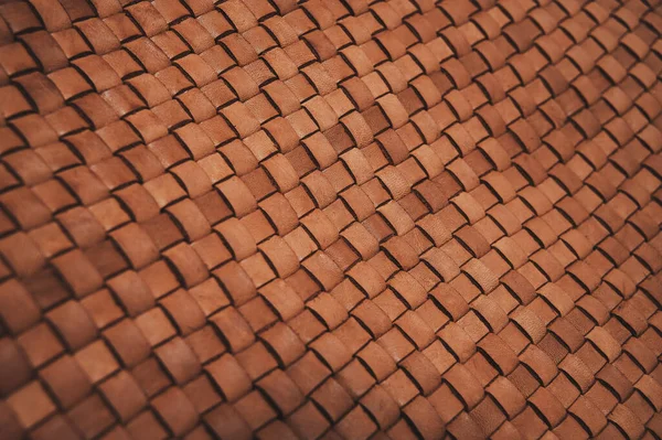Vintage brown braided leather texture. Leather woven together. Abstract clothing background. Shallow depth of field. Closeup.