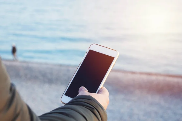 Deniz okyanus arka p bir akıllı telefon tutarak bir erkek eli