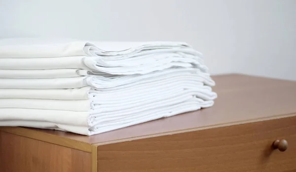 pile of white ironed linen on the wooden chest, on white backrou