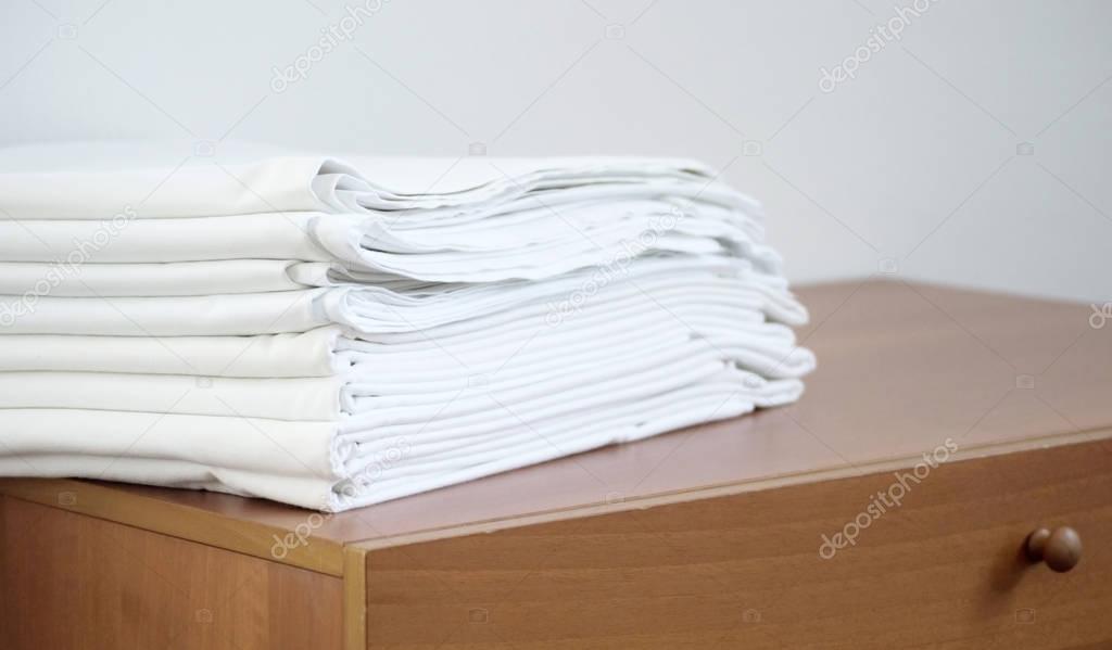 pile of white ironed linen on the wooden chest, on white backrou