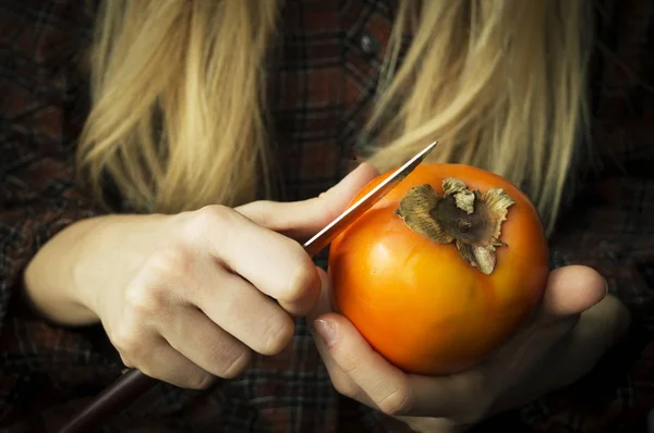 Una mujer rubia con caqui va a usar un cuchillo para cortar la fruta — Foto de Stock