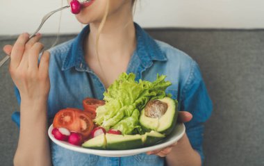 genç gülümseyen kadın evde taze sebze yemek. Yediğine vegan