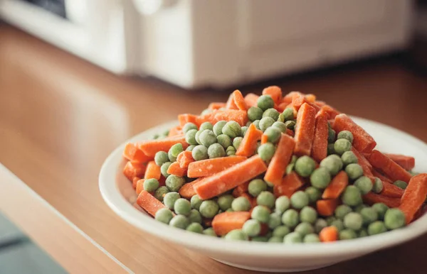 Dondurulmuş sebzeler üzerinde plat yakınındaki mocrowave, mutfak kapalı. Vegan 