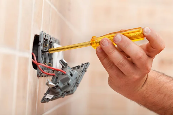 Electrician testing for electricity in electrical wall fixture — Stock Photo, Image