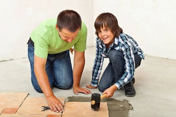 Chłopiec pomagał ojcu wprowadzania posadzki ceramiczne płytki — Zdjęcie stockowe