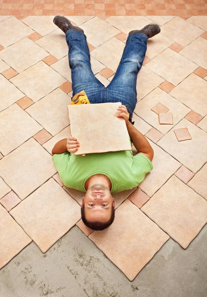 Man lying on unfinished floor tiling — Stock Photo, Image
