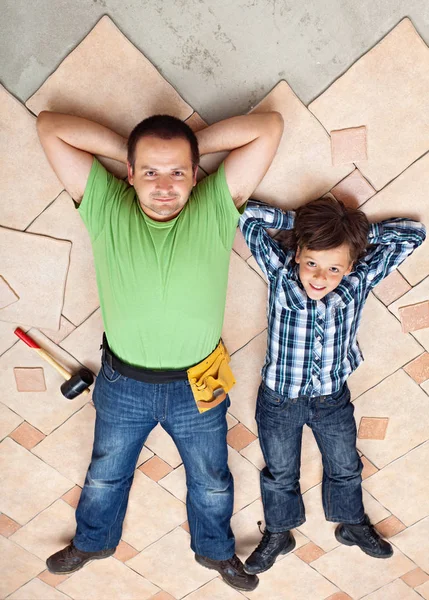 Pai e filho descansando sobre piso inacabado telhas superfície — Fotografia de Stock