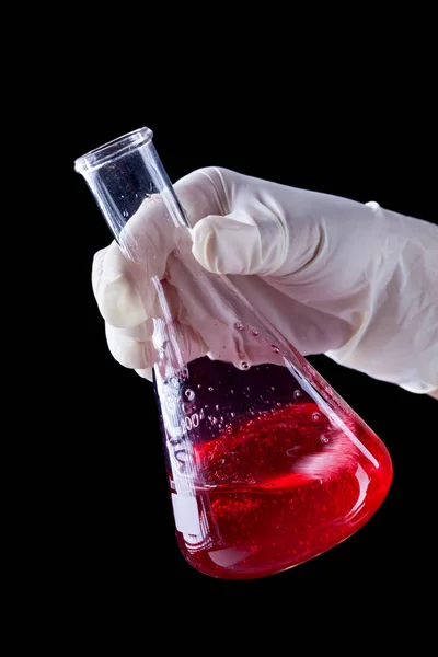 Hand stirring and shaking red liquid in Erlenmayer flask — Stock Photo, Image