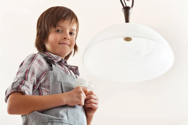 Niño cambiando una bombilla en la lámpara de techo —  Fotos de Stock