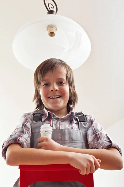 Мальчик меняет лампочку в потолочной лампе — стоковое фото