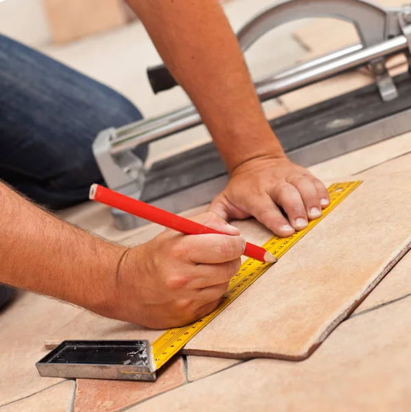 Colocação de telhas cerâmicas piso - homem mãos marcação telha a ser cortada, c — Fotografia de Stock