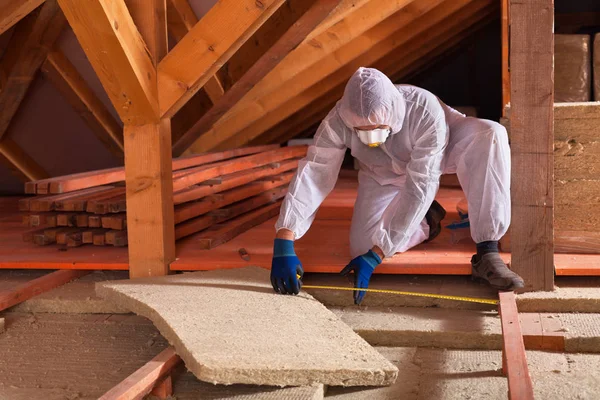 Mann legt Steinwolle-Platten auf dem Dachboden eines Hauses — Stockfoto