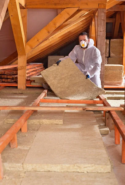 Homem coloca isolamento térmico de lã de rocha entre andaimes de madeira — Fotografia de Stock