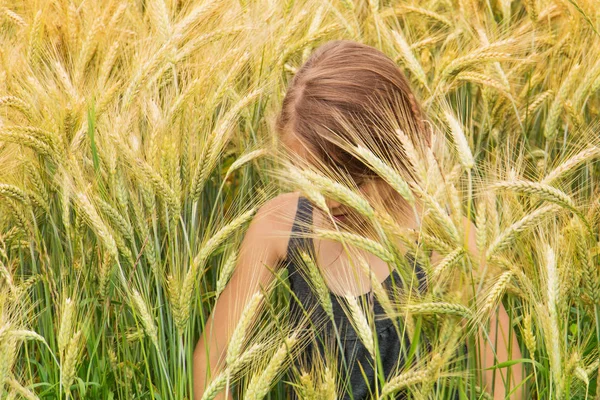 Маленькая девочка погрузилась под шипы созревшего зернового поля — стоковое фото